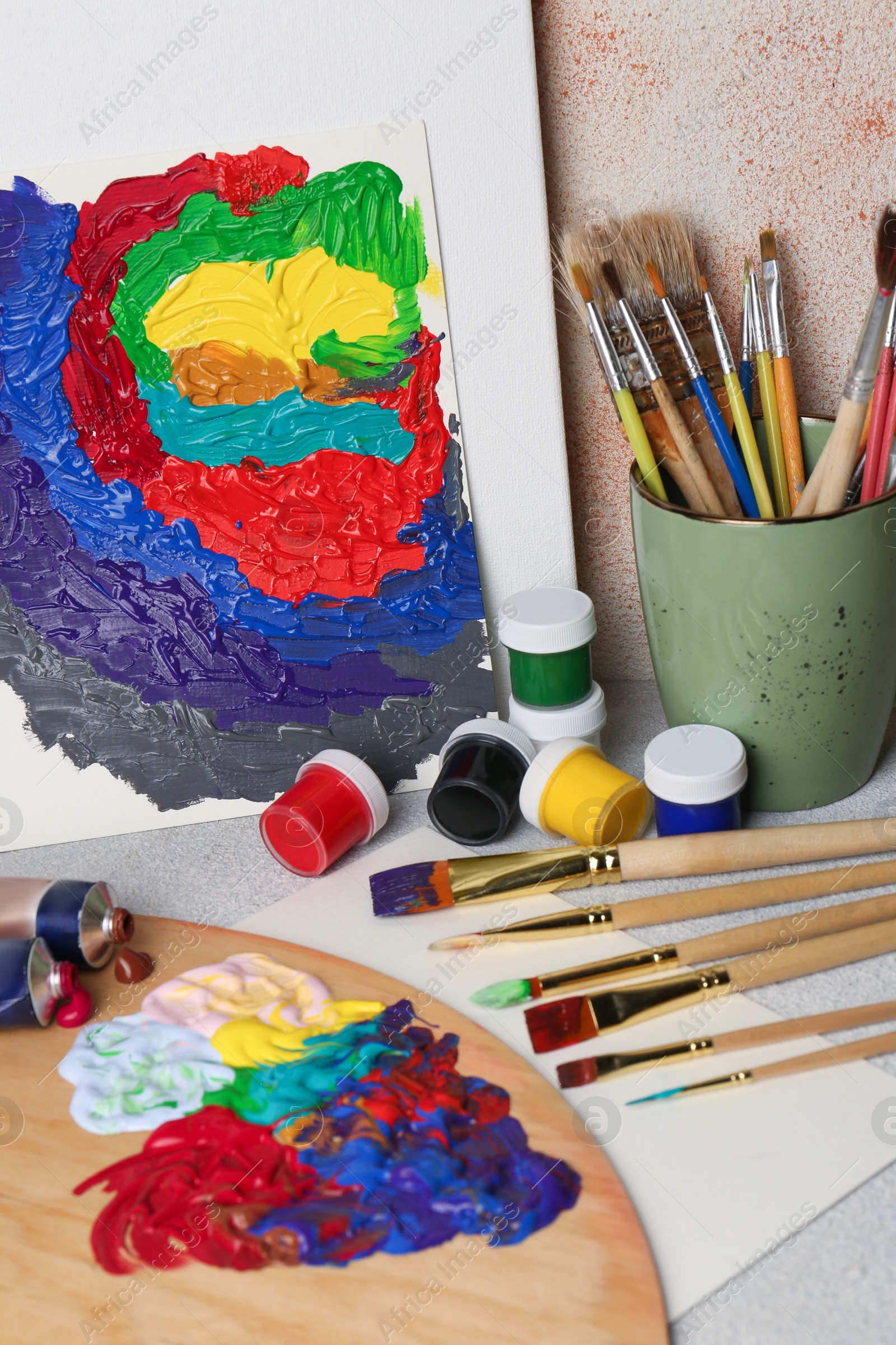 Photo of Abstract colorful painting and different artist's tools on textured table