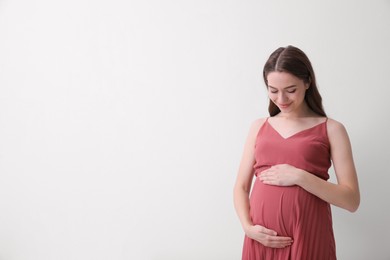 Photo of Beautiful young pregnant woman on light background. Space for text