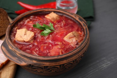 Photo of Tasty borscht in bowl on grey wooden table, closeup