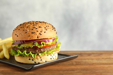 Photo of Burger with delicious patty and french fries on wooden table, space for text
