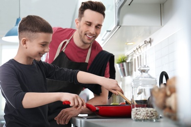 Photo of Dad and son cooking together in kitchen