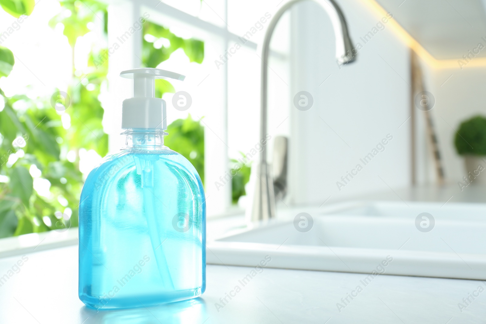 Photo of Bottle of antibacterial soap near sink indoors. Personal hygiene during COVID-19 pandemic