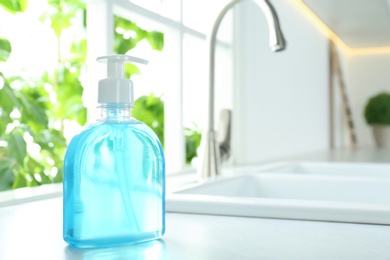 Bottle of antibacterial soap near sink indoors. Personal hygiene during COVID-19 pandemic