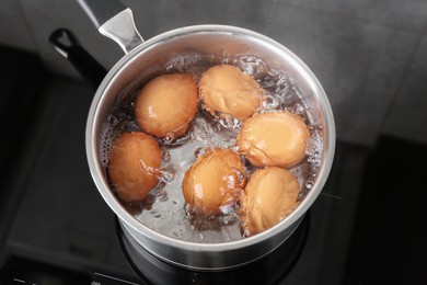 Photo of Chicken eggs boiling in saucepan on electric stove, above view