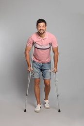 Photo of Full length portrait of man with crutches on grey background