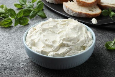 Photo of Tasty cream cheese and basil on grey table