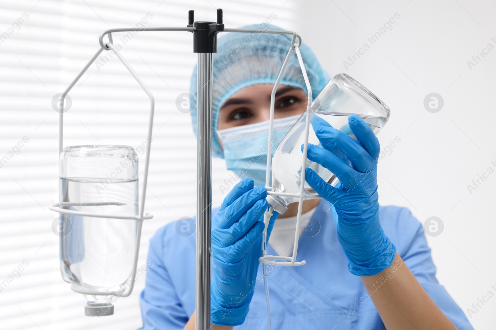 Photo of Nurse setting up IV drip in hospital, selective focus