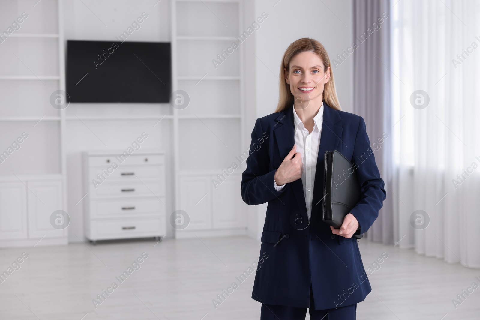 Photo of Happy real estate agent with leather portfolio in new apartment