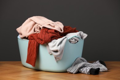 Photo of Laundry basket with clothes near dark grey wall