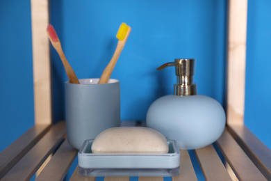 Shelving unit with toiletries near blue wall indoors. Bathroom interior element