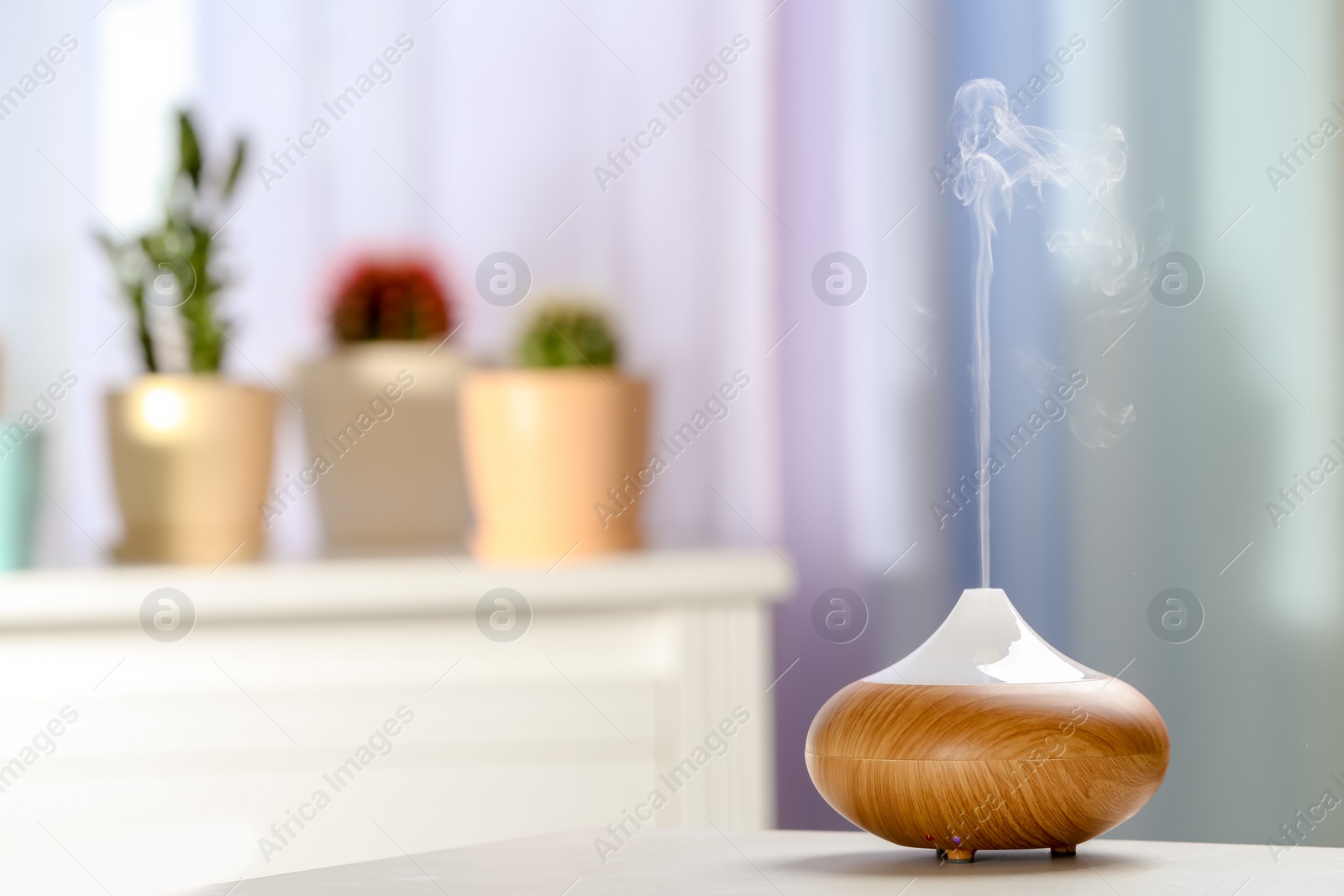 Photo of Aroma oil diffuser on table in room. Air freshener