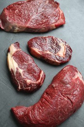 Photo of Pieces of raw beef meat on grey table, above view