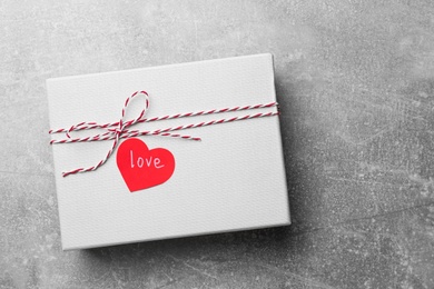 Photo of Gift box and heart shaped sticker with word LOVE on grey background, top view