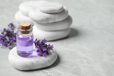 Stones, bottle of essential oil and lavender flowers on marble table. Space for text