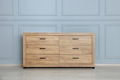 Photo of Wooden stylish chest of drawers near grey wall indoors