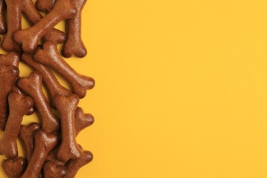 Photo of Bone shaped dog cookies on orange background, flat lay. Space for text