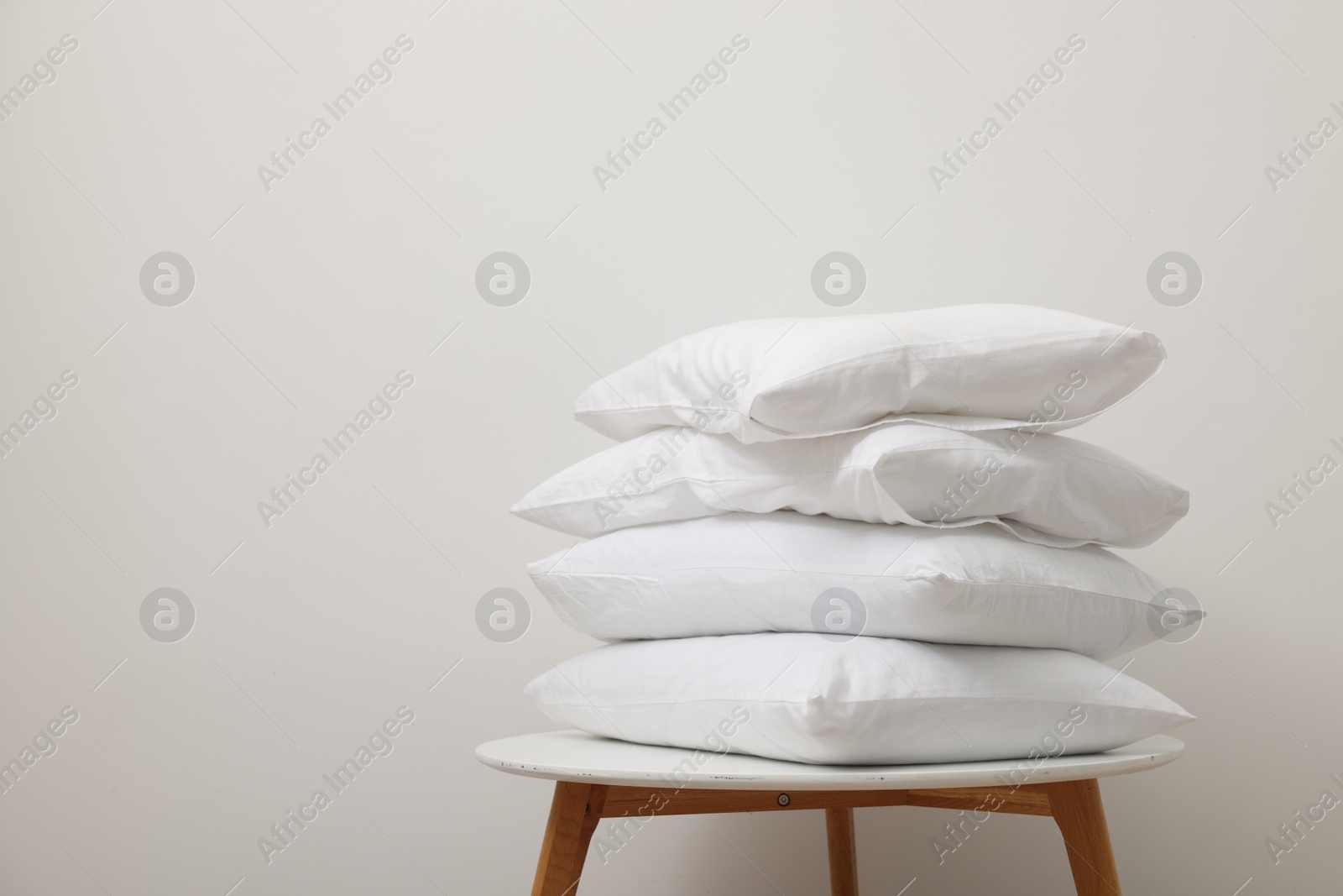 Photo of Soft pillows on side table near light wall, space for text