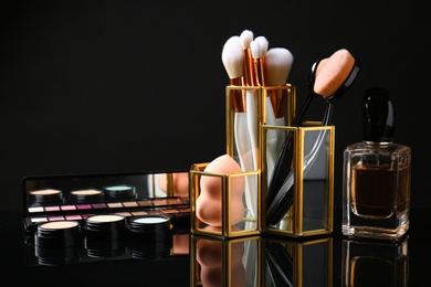 Set of makeup products and brushes on dark background