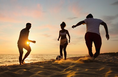 Photo of Friends playing football on beach at sunset