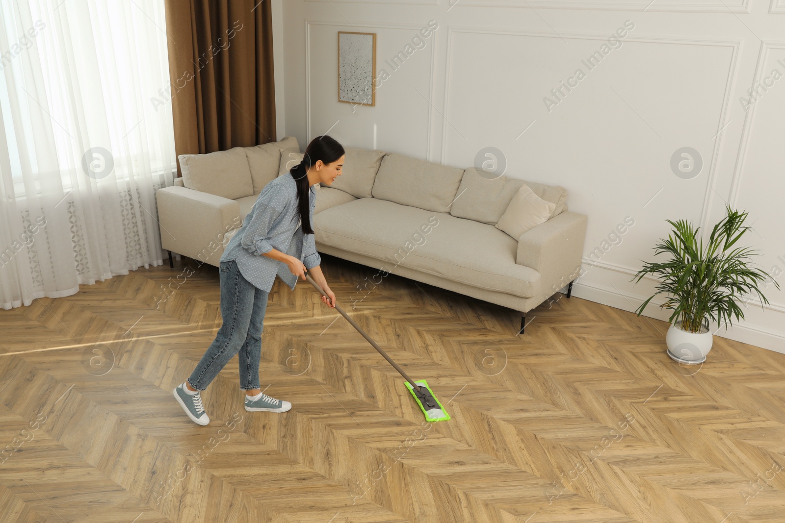 Photo of Woman cleaning floor with mop at home