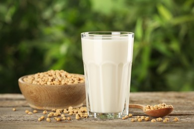 Photo of Glass with fresh soy milk and grains on white wooden table against blurred background