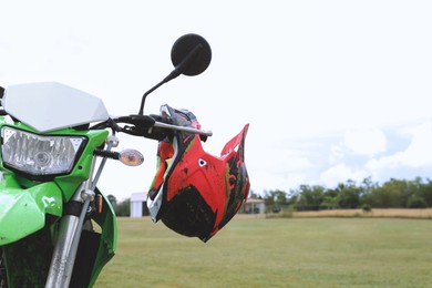 Photo of Stylish green cross motorcycle with helmet outdoors, space for text