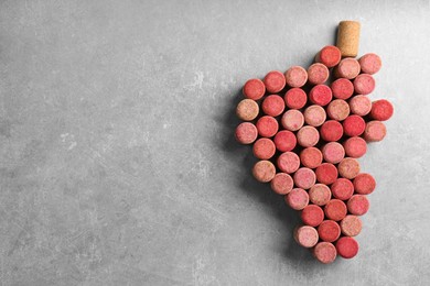 Grape made of wine bottle corks on grey table, top view. Space for text