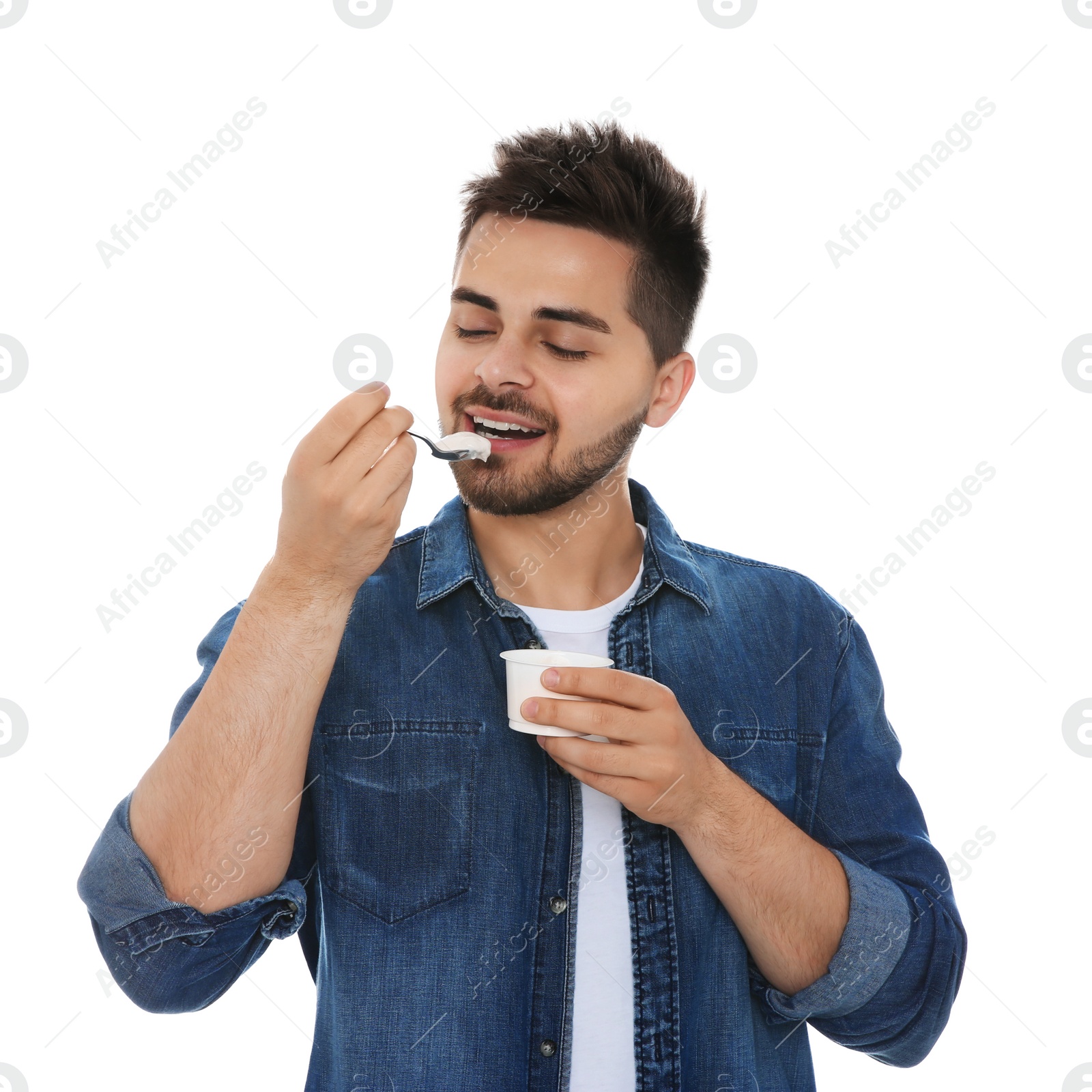 Photo of Happy young man eating tasty yogurt on white background