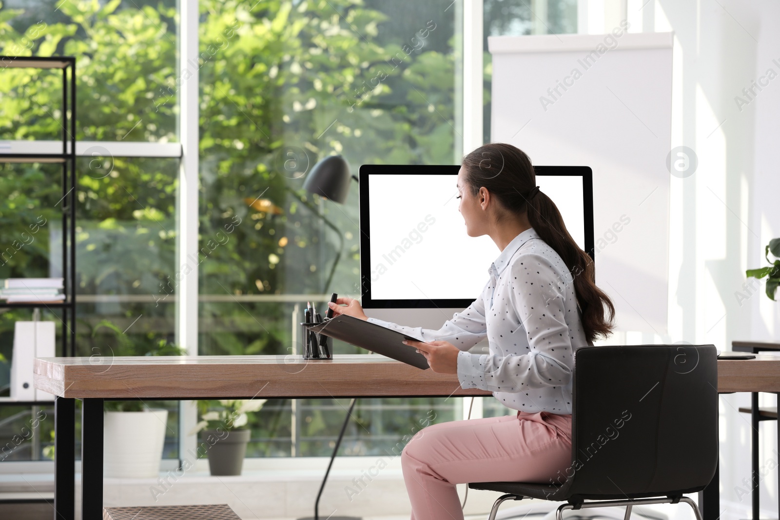 Photo of Young woman working at table in modern office