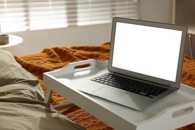 Photo of White tray with modern laptop on bed indoors
