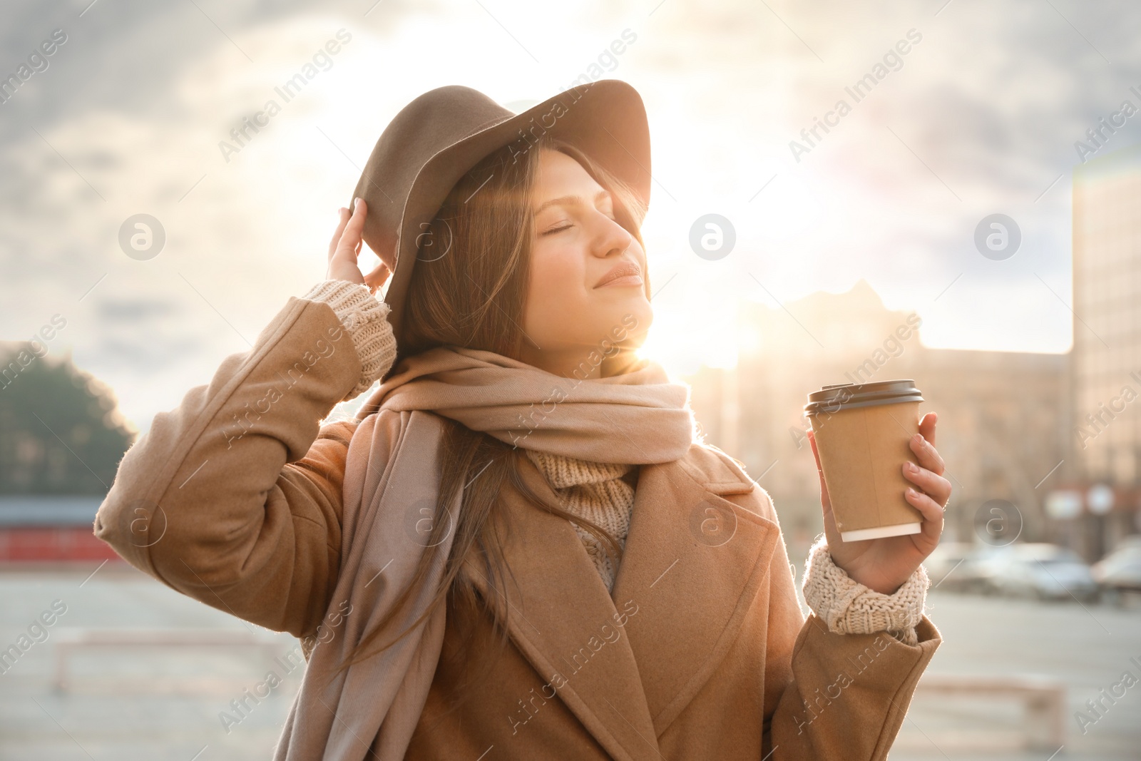 Photo of Young woman with cup of coffee on city street in morning