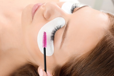 Young woman undergoing eyelash extensions procedure, closeup