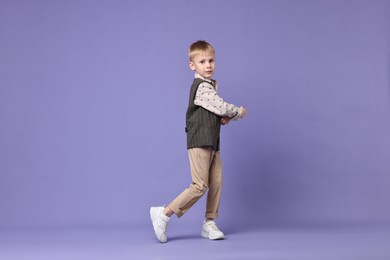 Happy little boy dancing on violet background. Space for text