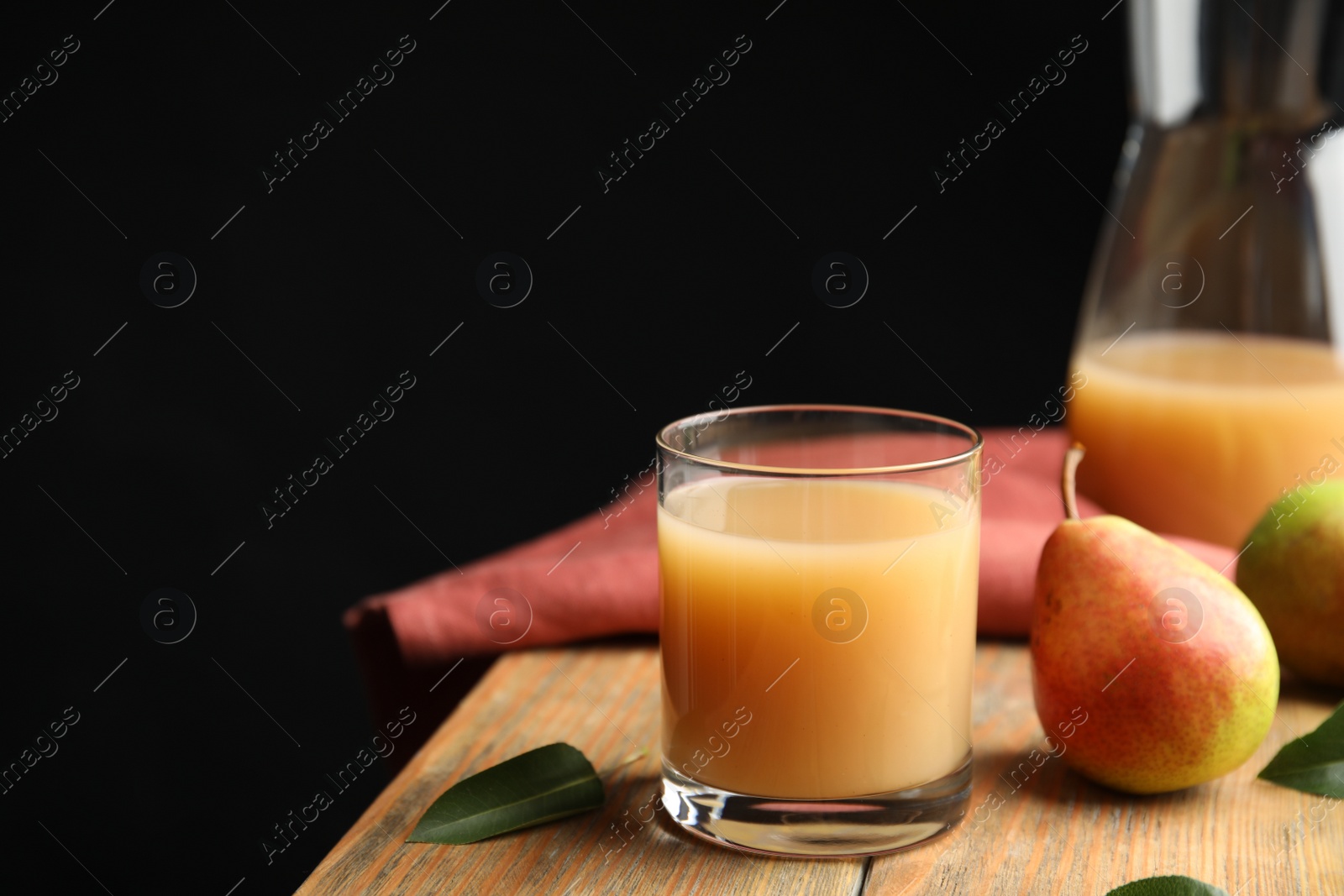 Photo of Fresh pear juice in glass and fruits on wooden table. Space for text