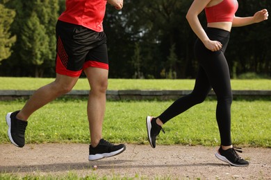 Photo of Healthy lifestyle. Couple running in park on sunny day, closeup