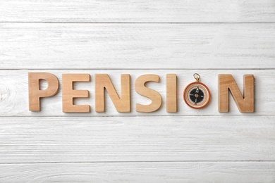 Photo of Flat lay composition with word PENSION and compass on wooden background