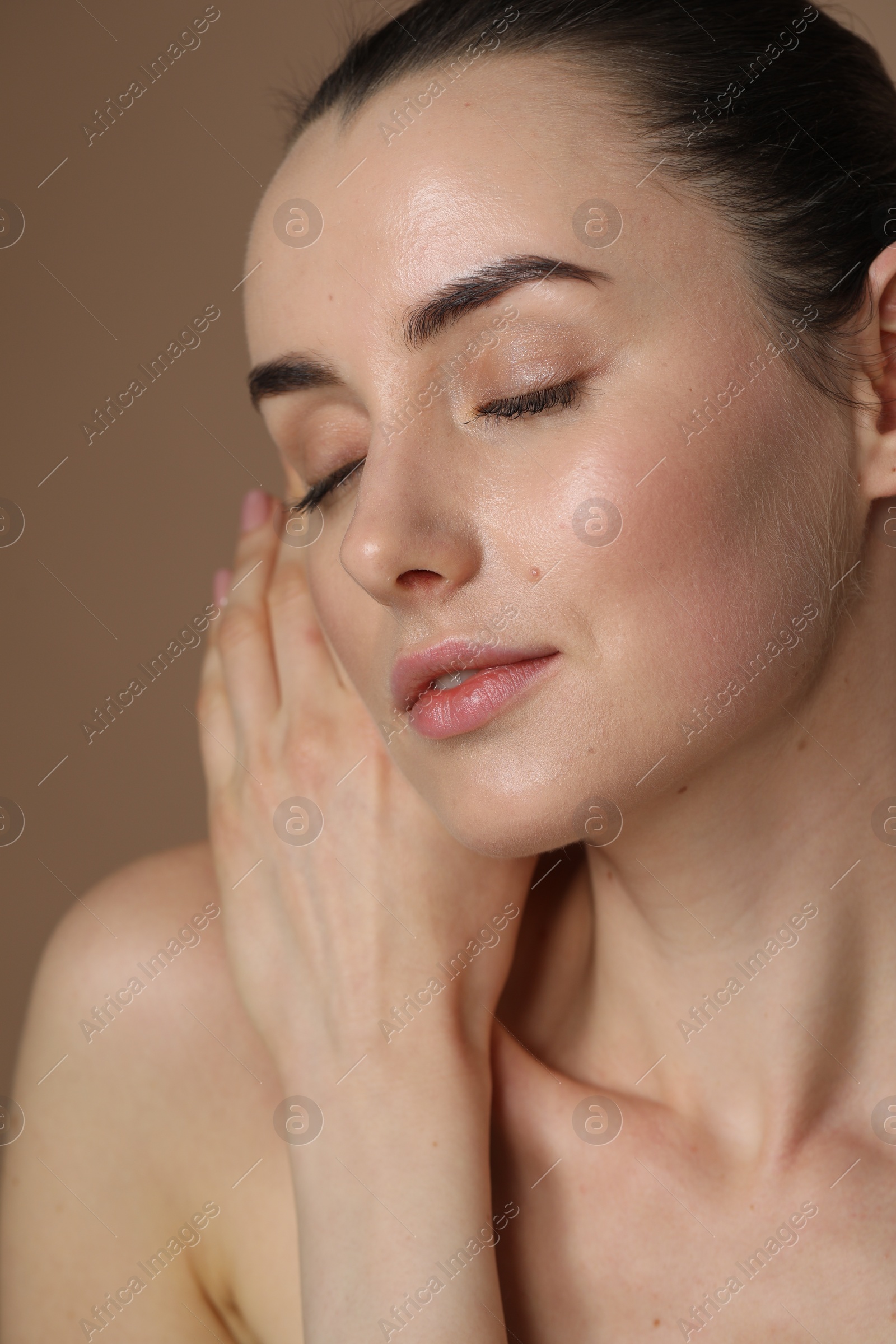 Photo of Beautiful young woman with healthy skin on light brown background, closeup