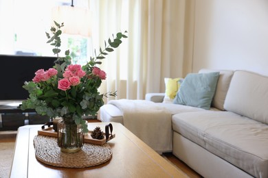 Photo of Beautiful bouquet of roses and eucalyptus branches in vase on table at home. Space for text