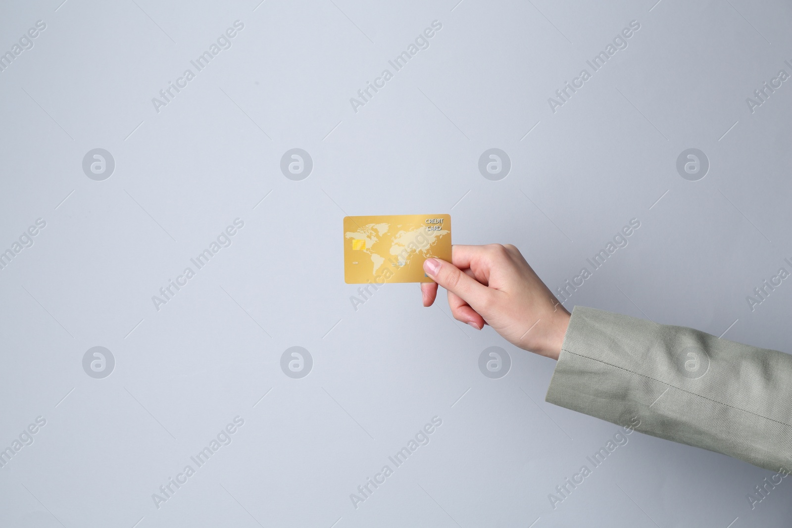 Photo of Woman holding credit card on light grey background, closeup