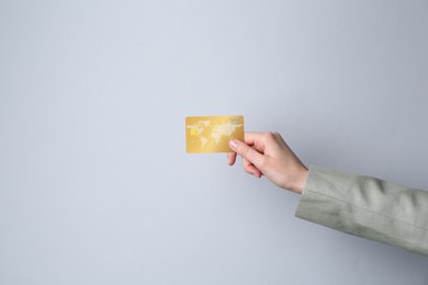 Photo of Woman holding credit card on light grey background, closeup