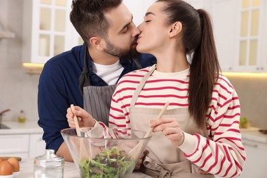 Photo of Lovely couple kissing while cooking in kitchen