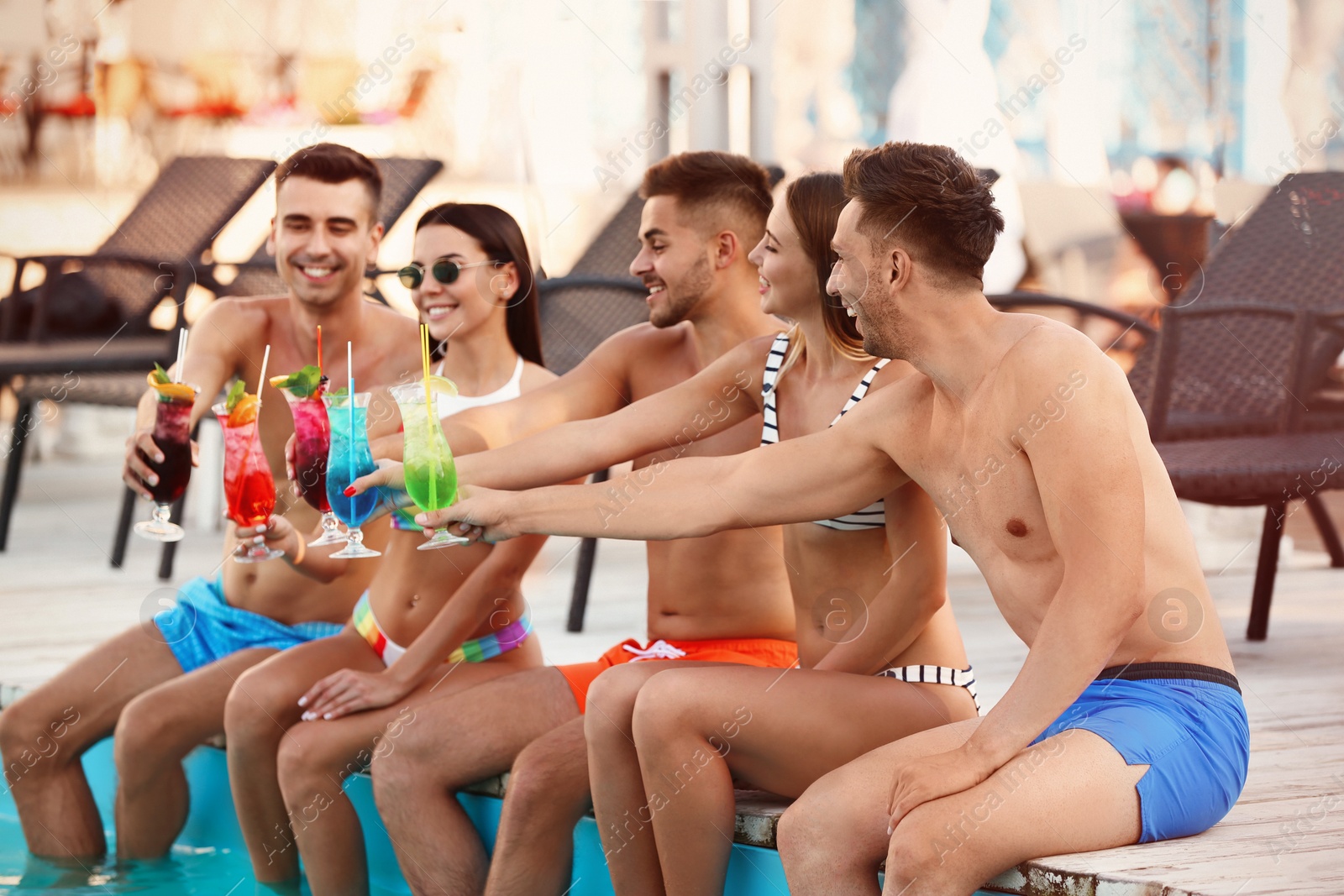 Photo of Happy young friends with refreshing cocktails near swimming pool