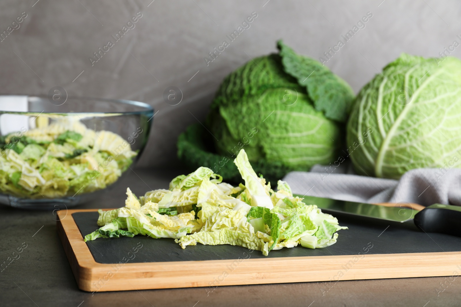 Photo of Cutting board with chopped savoy cabbage on table