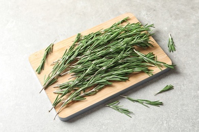 Wooden board with fresh rosemary on table