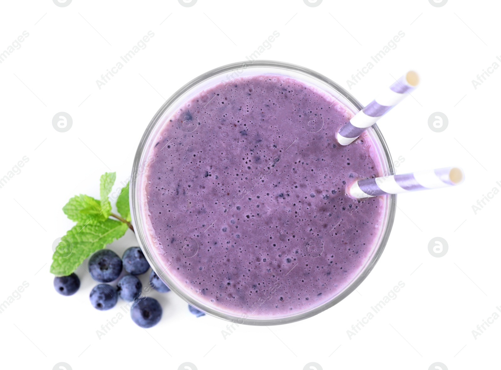 Photo of Tasty fresh milk shake in glass and blueberries on white background, top view