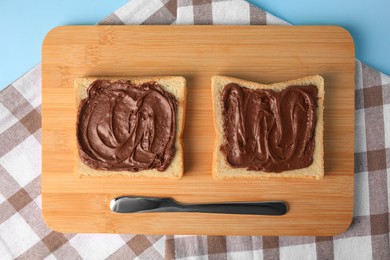 Photo of Tasty toasts with chocolate paste served on light blue background, top view