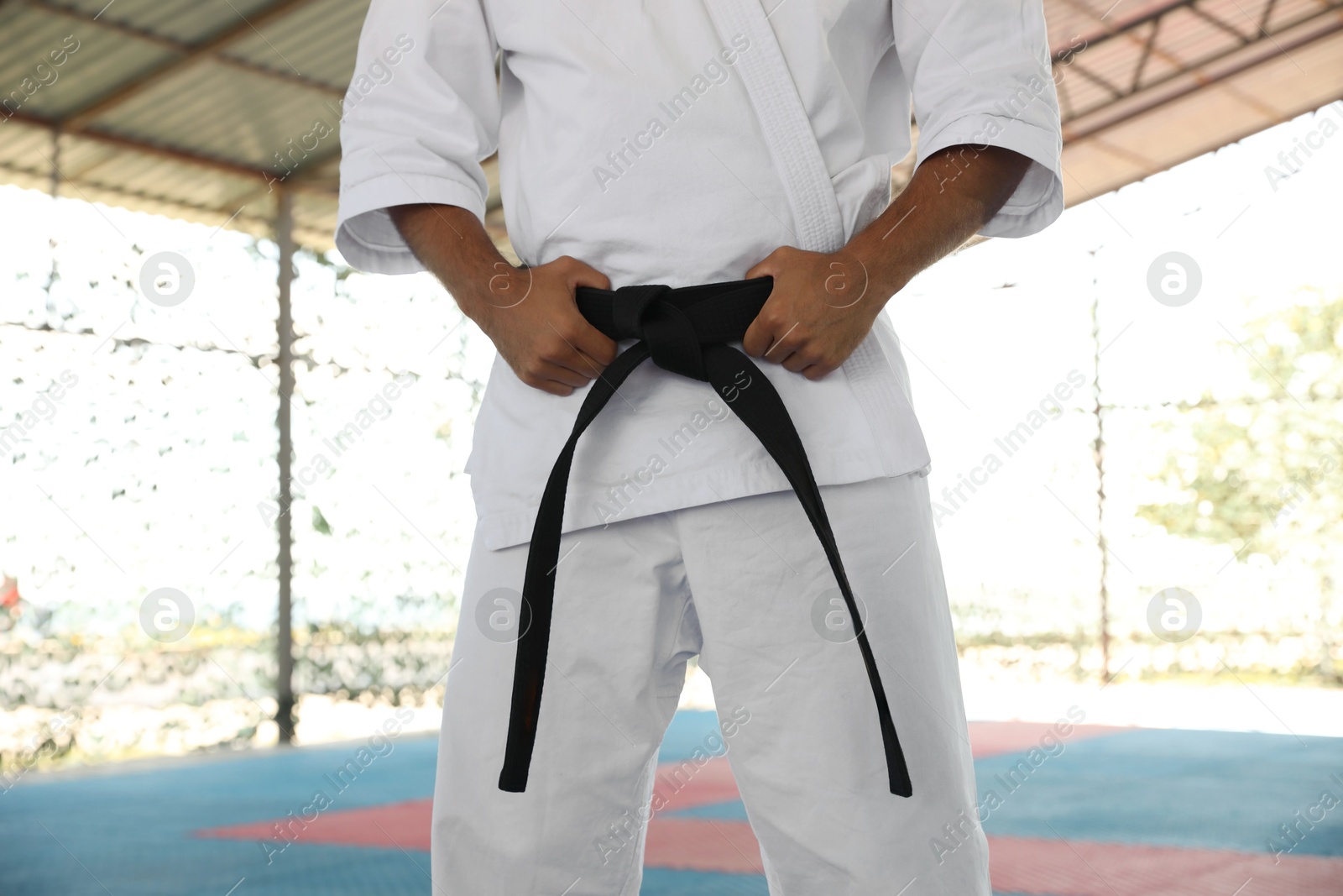Photo of Karate coach wearing kimono and black belt at outdoor gym, closeup