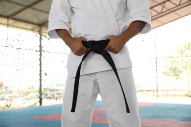 Karate coach wearing kimono and black belt at outdoor gym, closeup