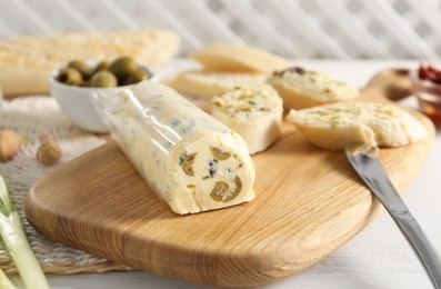 Photo of Tasty butter with olives, green onion, bread and knife on white wooden table