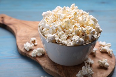 Photo of Tasty popcorn on light blue wooden table, closeup